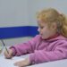 Дитина навчається писати в рядку за шкільною партою